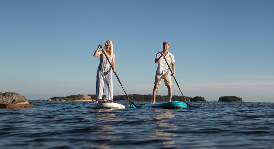 TEST SUP lautailu, nainen ja mies meloo sup laudoilla merellä, taustalla saaria - Santalahti Resort - Kotka Finland