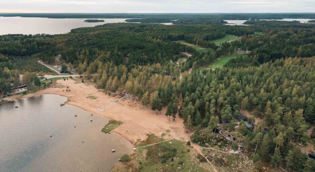 Ilmakuva kuvattu luoteseen, edustalla Santalahden uimaranta ja Luontokylpylä ja saunat, taustalla golfkenttä ja leirintäalue - Santalahti Resort - Kotka Finland